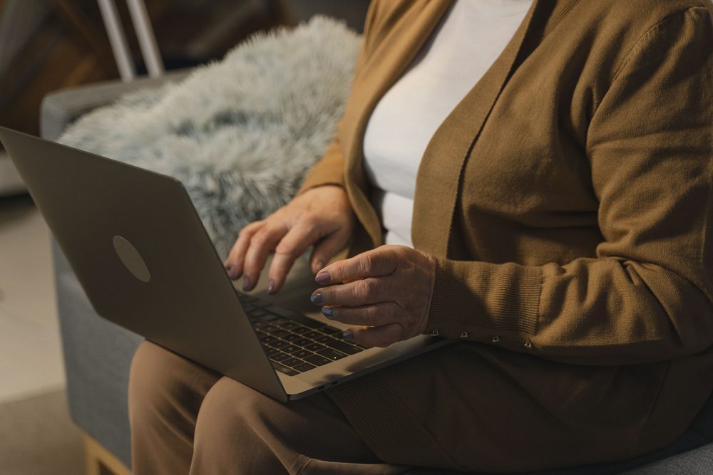 Person using a laptop while relaxing on a sofa at home